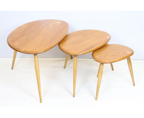 Ercol elm pebble nest of tables each having oval tops raised on tapering turned legs. Ercol sticker to underside of largest t