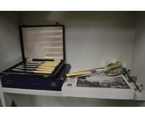 A pair of silver plated knife rests; various boxes cutlery; two berry spoons; and a set of place mats 