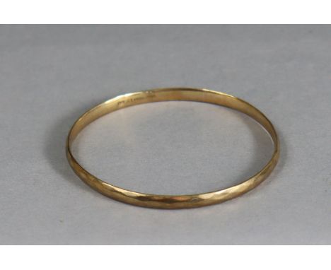 A 9ct gold (metal core) stiff bangle with faceted surface.