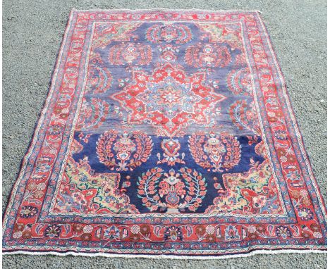 A north west Persian carpet, the blue field with central polychrome medallion and vases of flowers, within a red arabesque bo