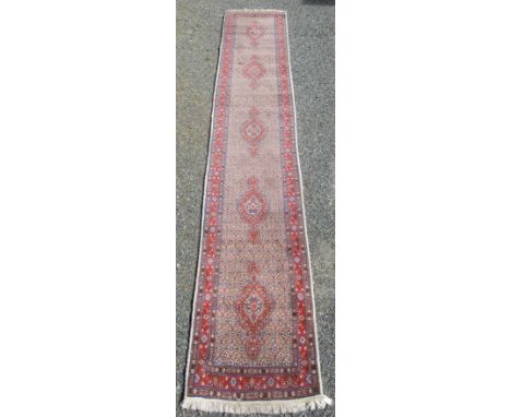 A west Persian runner, the ivory field with five polychrome lobed medallions within three borders, 491 x 81cm. 