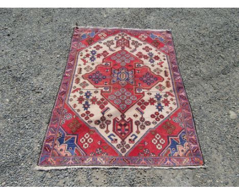 A north west Persian rug, the ivory field with a central red pole medallion within a blue serrated leaf and gul border, 153 x