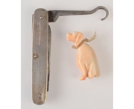 A carved pale pink coral seated hound fob and an Edwardian silver mounted, small pocket knife with a blade and button hook.