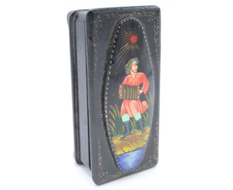 A continental papier mache rectangular box, the hinged cover with an oval panel decorated with a seated figure playing an acc