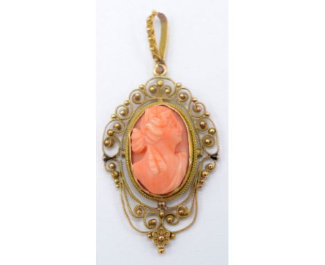 A coral cameo set in an ornate gold filigree pendant mount.