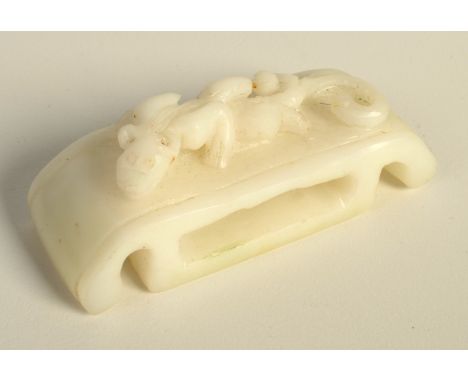 A Chinese white jade rectangular bodied belt slide with under turned ends supporting the slide, the upper body carved in reli