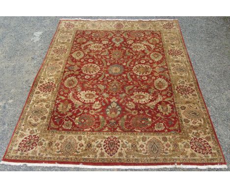 An Indian carpet, the red ground with an all over design of flowering, scrolling vines and large palmettes within an ivory si