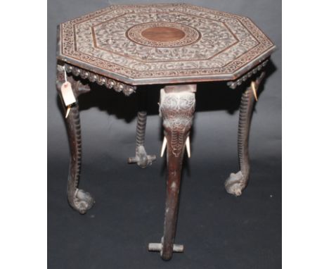 An Indian carved ebonised, octagonal table on four elephant head and trunk legs.