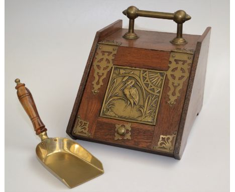 An Aesthetic Movement oak brass mounted coal box, the slope front with a square brass panel decorated with a stork amongst re