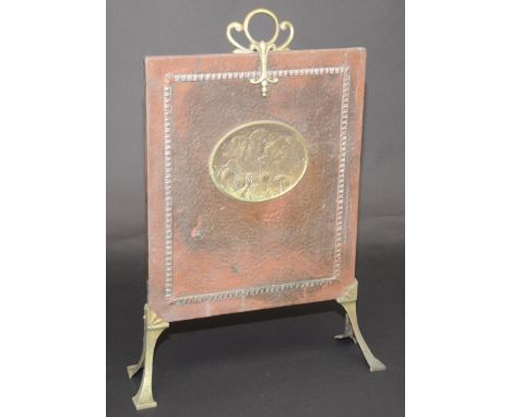 A copper firescreen, early 20th century, set with a brass oval plaque of three classical ladies, height 69.5cm.