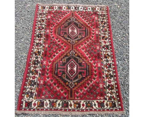 A Shiraz rug, south west Persia, the red field with two linked serrated medallions, with an ivory meandering vine and flowerh