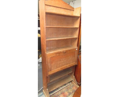 A Cotswold School light oak bureau bookcase, the upper section with open chamfered shelves beneath an architectural pediment,
