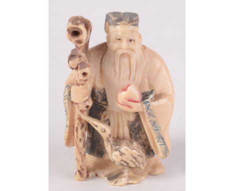 A Chinese part coloured carved ivory netsuke, an elderly gentleman wearing a robe, carrying a fruit and holding a staff and w