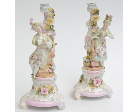 A pair of continental porcelain four branch candelabra, each decorated with figures of classical ladies and flowers, on three