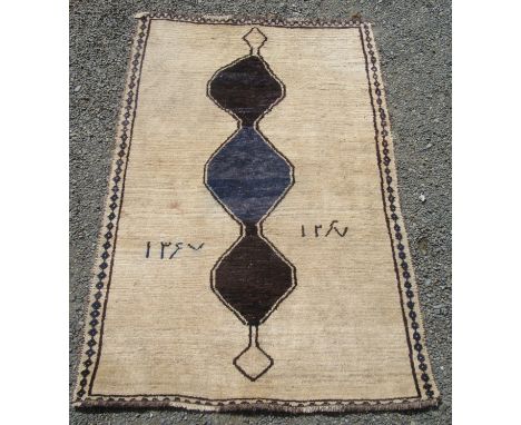 A Gabbeh rug, the plain ivory field with Islamic script and a triple linked medallion, 210 x 136cm.