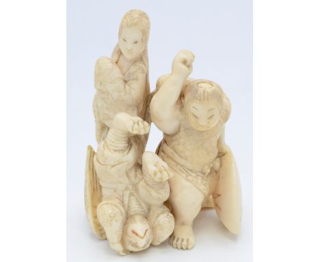 A Japanese ivory okimono group carved as an oni, an upside down kappa, a female figure looking on, height 7.5cm.   Condition 