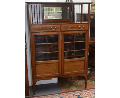 An Edwardian mahogany display cabinet in Arts and Crafts style, the top with wide shelf over slender pillars and a mirror, th