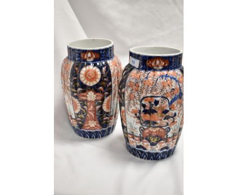 A pair of Meiji period Japanese Imari porcelain vases, of fluted form and decorated in the typical palette with panels of fol