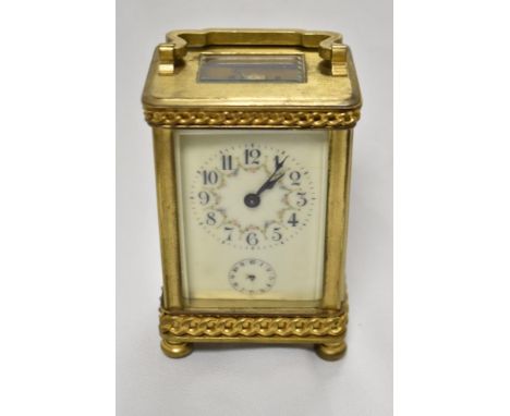 An early 20th Century French carriage clock, with shaped handle, bevelled glass case, a hand painted floral enamel dial and s
