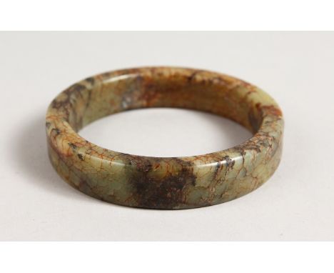 A MOTTLED JADE BANGLE. 3ins diameter.