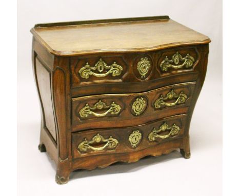 A LOUIS XV STYLE FRENCH OAK SERPENTINE FRONT COMMODE, comprising two short and two long drawers, all with ornate cast brass h