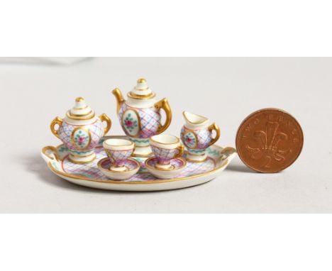 A MINIATURE LIMOGES PORCELAIN TEA SET painted with roses comprising tray, teapot, milk jug, sugar basin, two cups and saucers