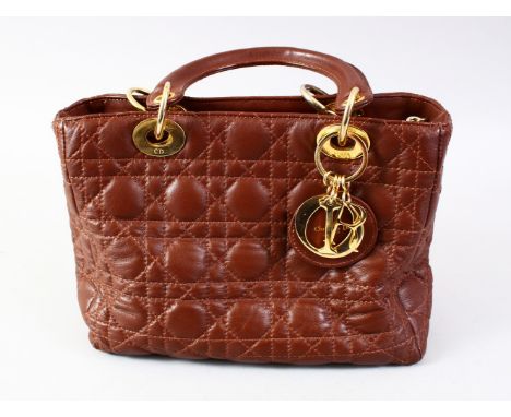 A CHRISTIAN DIOR BROWN LEATHER BAG with red and silver lining.