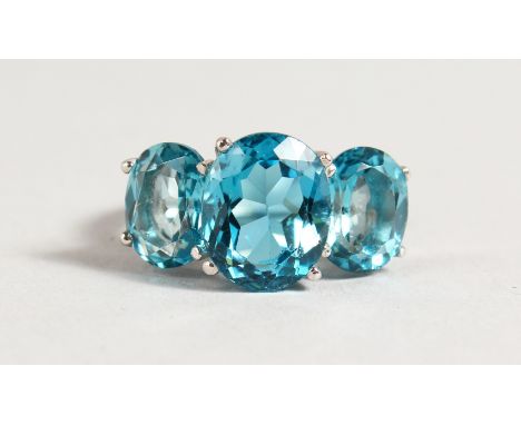 A SILVER THREE STONE BLUE TOPAZ RING.