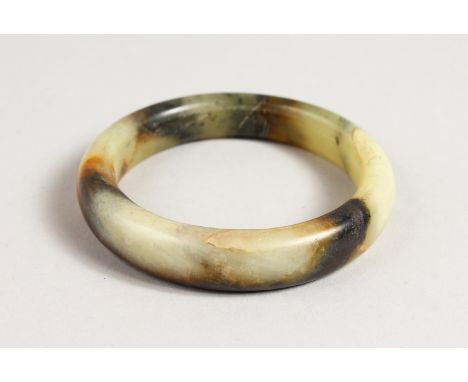 A MOTTLED JADE BANGLE. 3ins diameter.