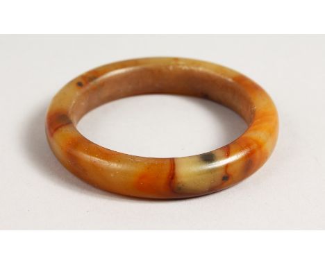A MOTTLED JADE BANGLE. 3ins diameter.