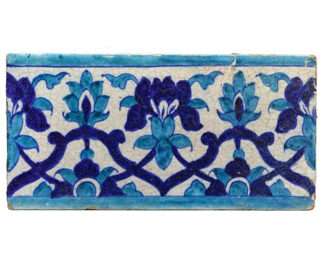 A turquoise and cobalt blue border tile, Multan, North India, 19th century, A swaying floral tendril intertwined with a strap
