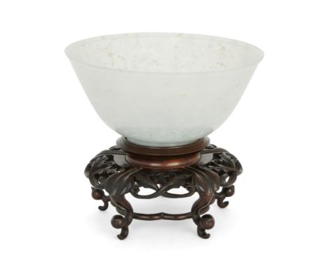 A Chinese pale green jadeite bowl, Early 20th century, The translucent stone with speckled dark green inclusions, 17cm diamet