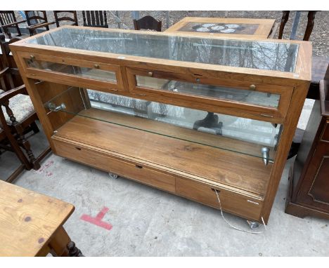 A 1970'S RETRO SOLID TEAK SHOP DISPLAY CABINET WITH UPPER LOCKABLE DROP DOWN PANELS, LOWER LIGHT UP GLASS SHELVES AND LOWER T