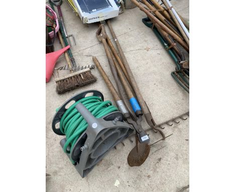 AN ASSORTMENT OF VINTAGE GARDEN TOOLS TO INCLUDE A RAKE, A HOE AND A HOSE PIPE ETC 