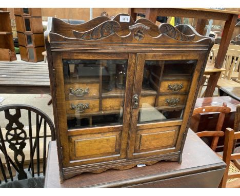 A LATE VICTORIAN TWO DOOR GLAZED TOBACCO CABINET ENCLOSING SHELVES, SEVEN DRAWERS AND SIX DIVISION PIPE RACK, 21" WIDE 