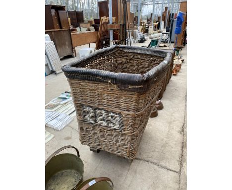 A LARGE VINTAGE WICKER LAUNDRY TROLLEY ON METAL WHEELS 