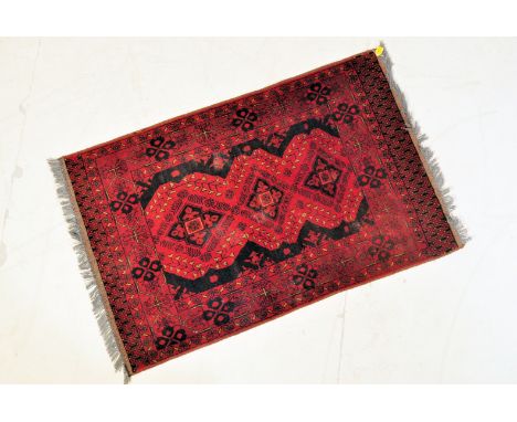 A vintage 20th century Persian Islamic rug having a red background, central geometric motifs set within a patterned border an