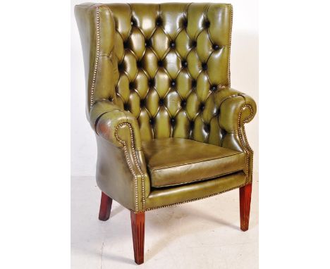 A vintage 20th century green leather button back Chesterfield style wingback armchair having studded button back over scrolle