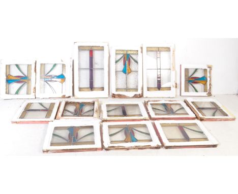 A large collection of vintage 20th century stained glass window panels within white painted wooden frames. Each having a vari