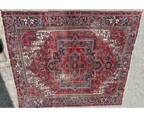 A vintage 20th century Persian Islamic rug / carpet having a red background with a blue geometric detailing. Tassels to each 