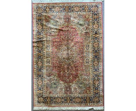A vintage 20th century Persian Islamic rug carpet having a red background with floral detailing and spandrels to the corner. 