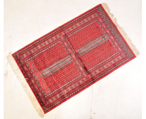 A vintage 20th century Persian Islamic rug carpet having a red background decorated with two central square panels set within