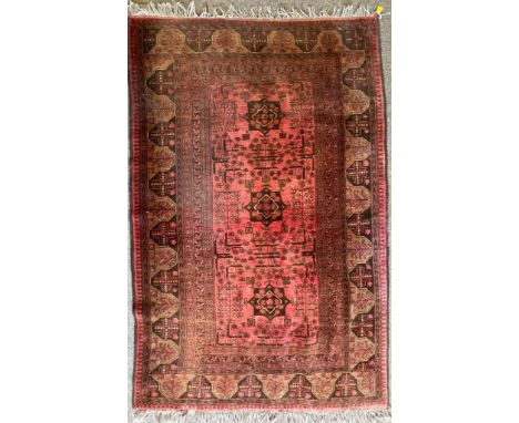 A vintage 20th century Persian Islamic rug having a red background with three central medallion motifs set within a geometric