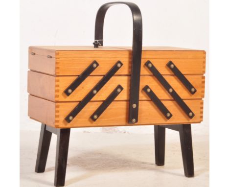 A retro vintage mid 20th century circa. 1960's teak sewing box having cantilever butterfly shelves raised on ebonised support
