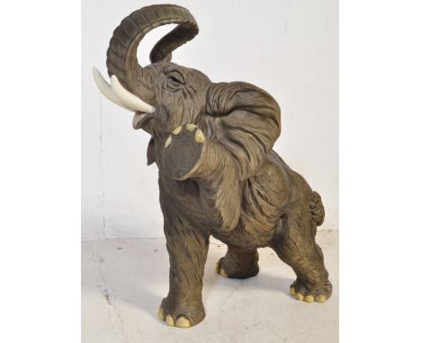 A vintage 20th century resin cast large figurine of an elephant. The elephant having polychrome decoration raising its front 
