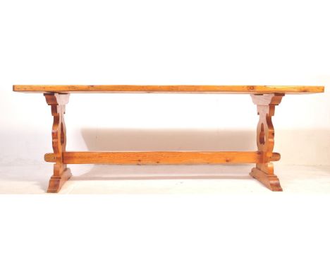 A early 20th century pine dining table having a rectangular top raised over a pierced colonial manner trestle base united by 