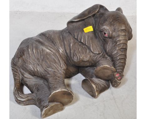 A large vintage retro 20th century resin elephant sculpture being hand painted and modelled lying down. Measures approx: 26x6