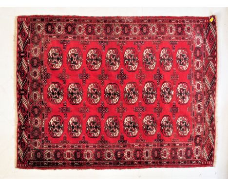 A vintage 20th century Persian Islamic rug / carpet having a repeating elephants foot motif set on a vibrant red background s