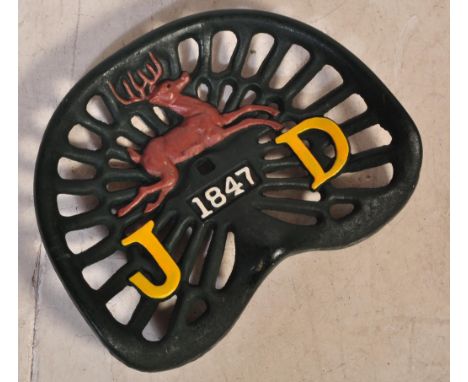 A 20th century cast iron John Deere pierced tractor seat. The seat being in a green colourway with raised letters J and D pri