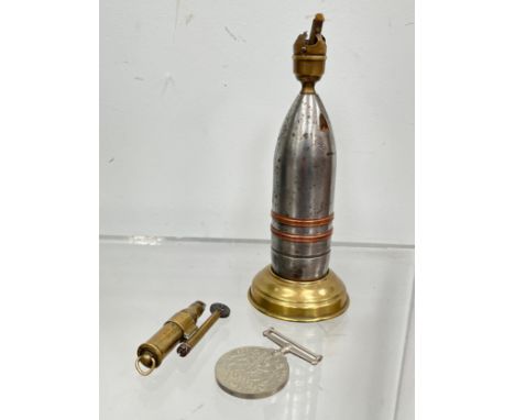 A trench art table lighter crafted from a shell head, together with a pocket lighter stamped R.K., and a WWII Defence medal (